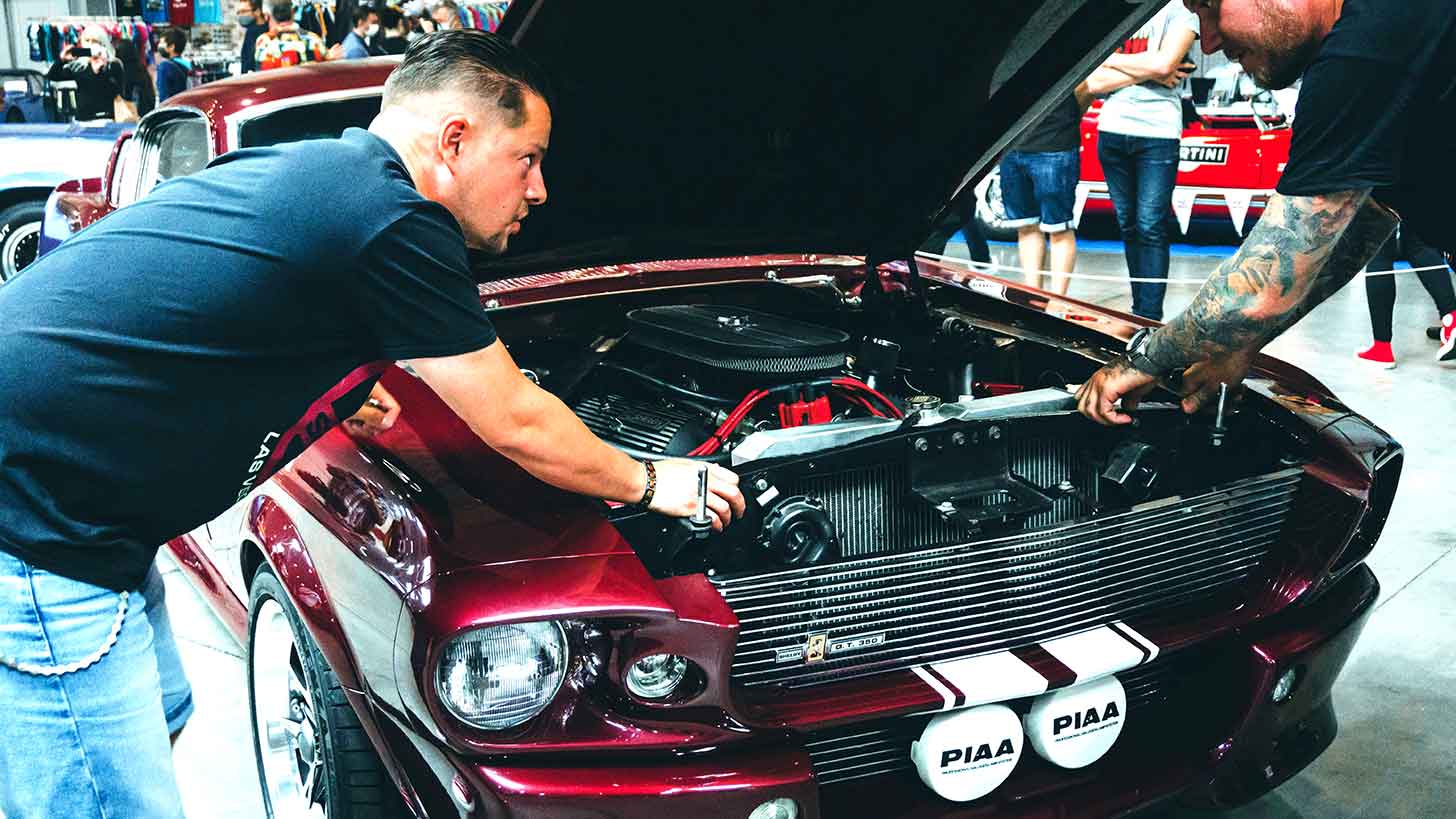 Guy looking under the hood at car show